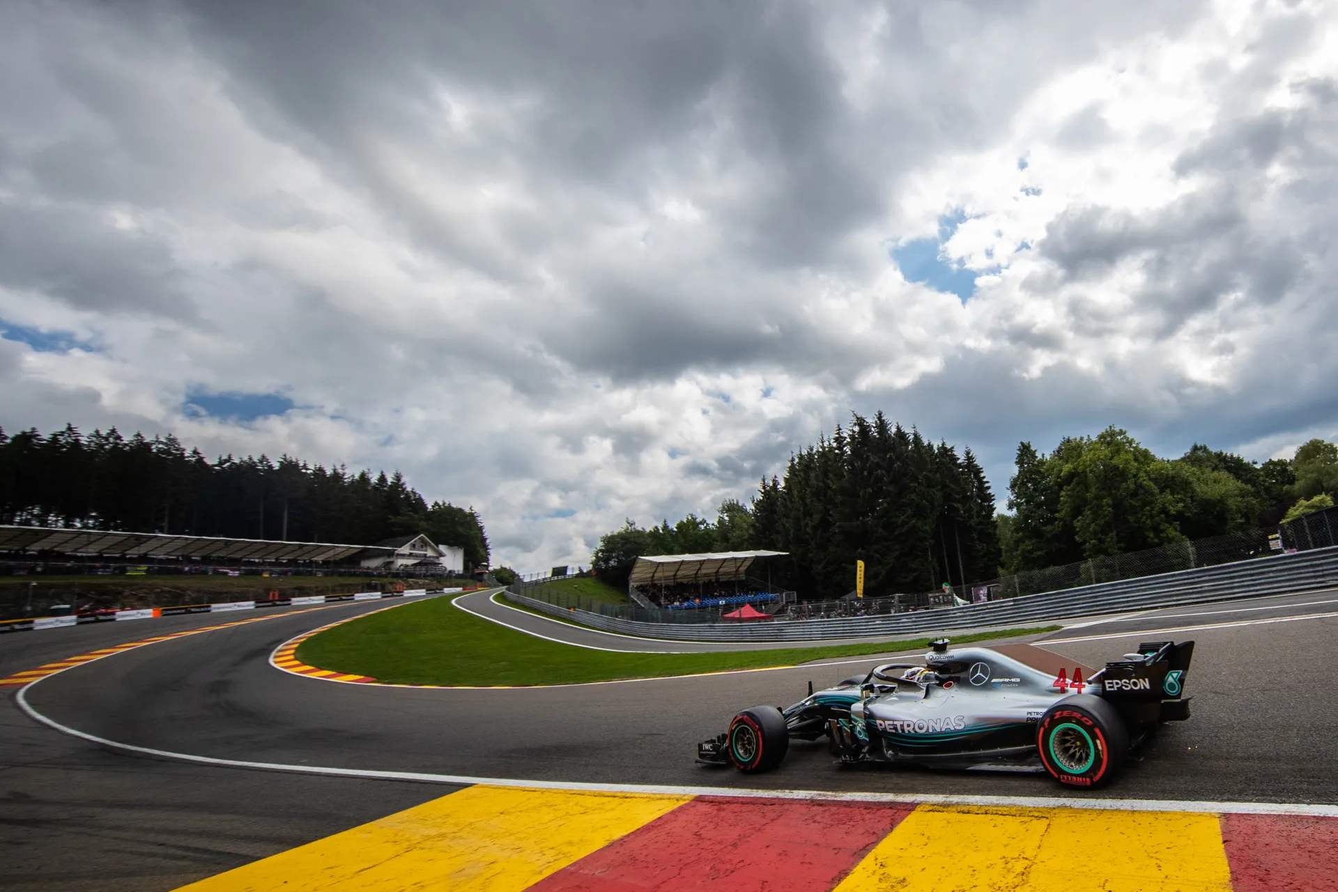 A Formula 1 car climbing through Eau Rouge at Spa, beneath the Ardennes sky